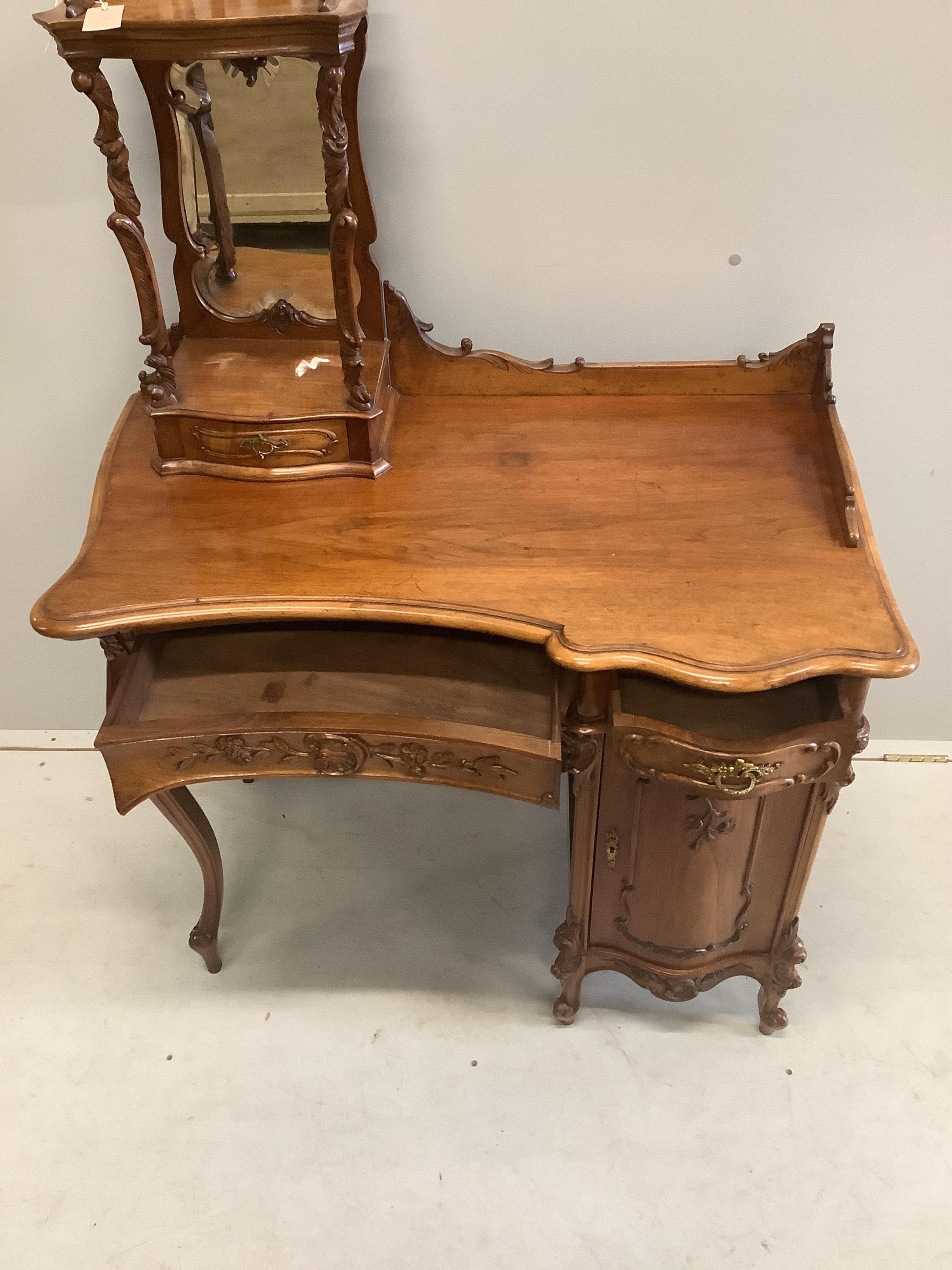 A Continental Art Nouveau carved walnut dressing table, width 92cm, depth 56cm, height 134cm. Condition - fair to good